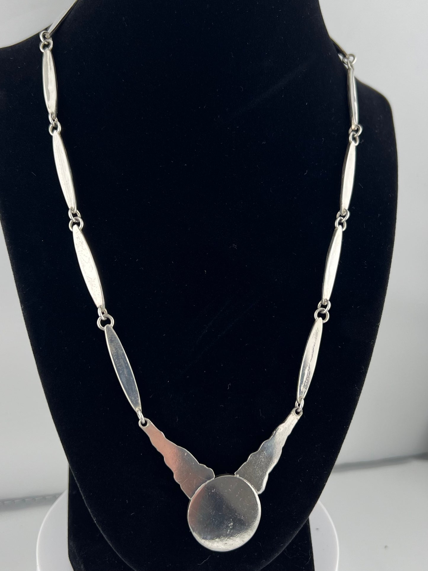 Backside Silver necklace on a black mannequin against a white background