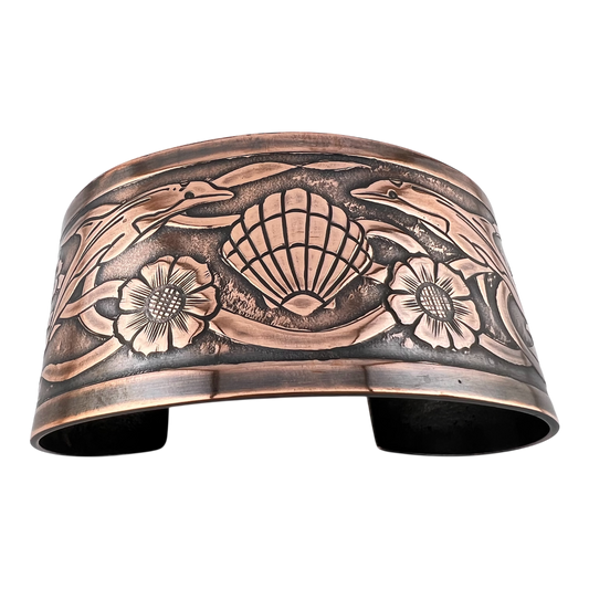 Copper cuff with undersea them featuring dolphins turtles shells and seaweed